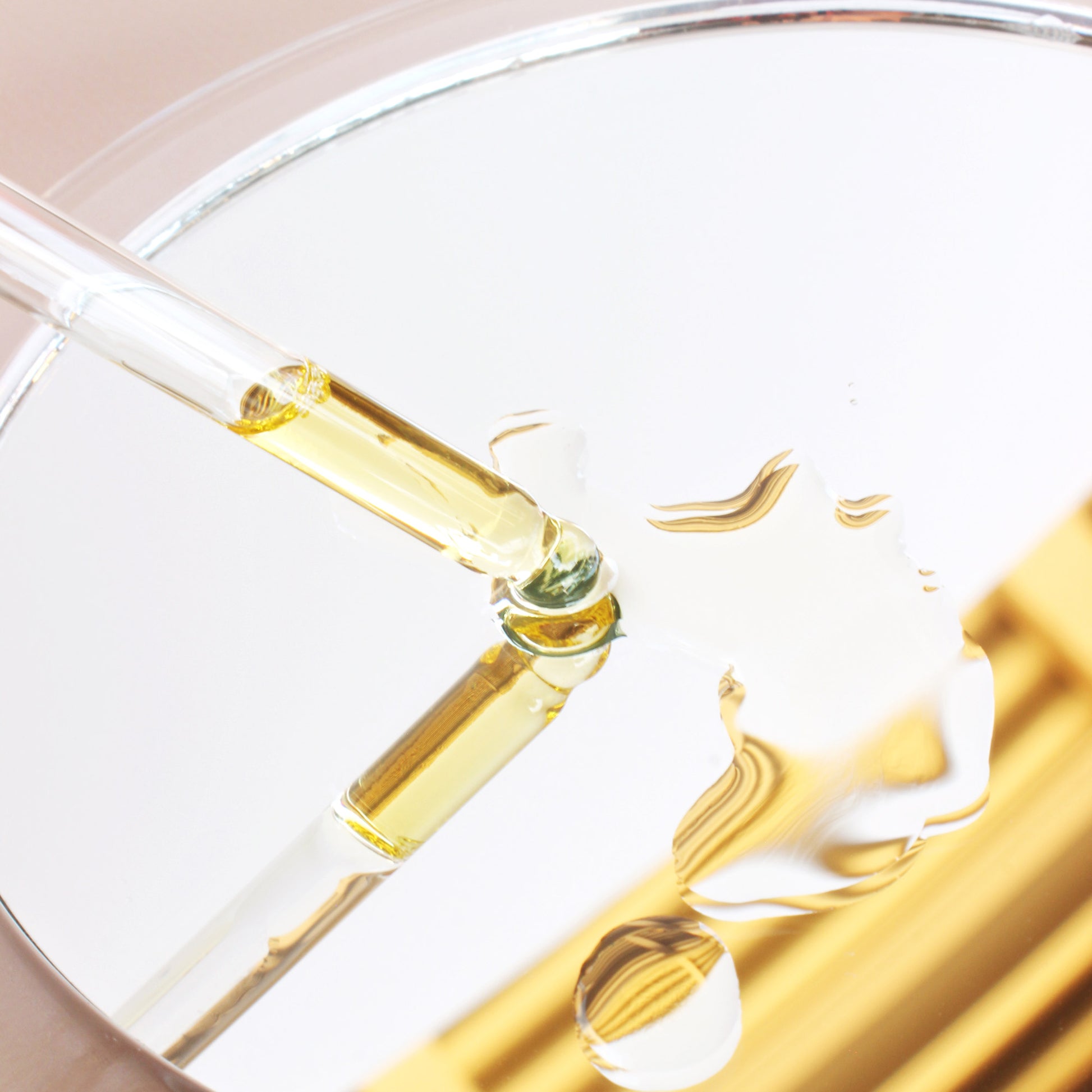 Pure Golden Jojoba Oil Close Up Showing Glass Dropper with Oil Droplets on Glass Petri Dish